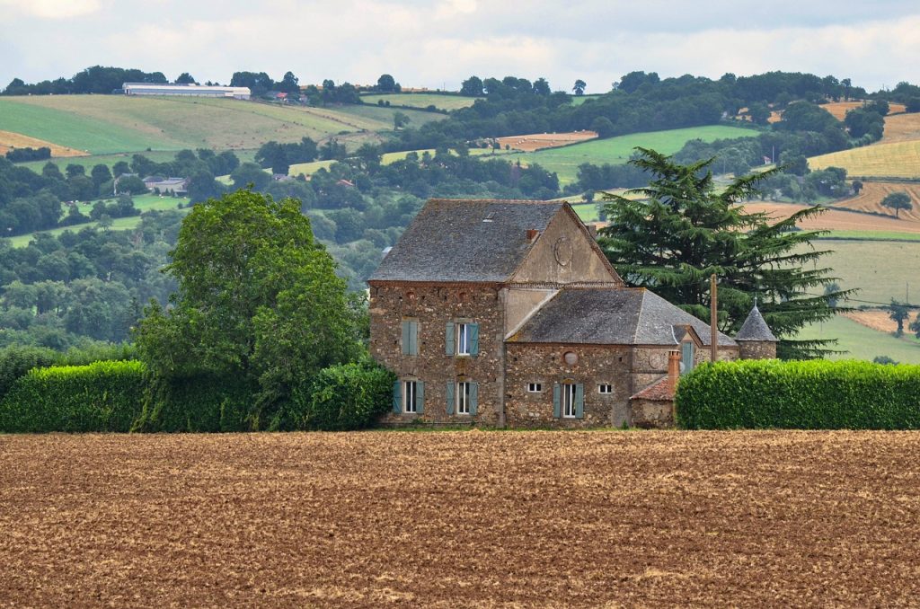 Countryside house with trees on the land and well-maintained hedges.